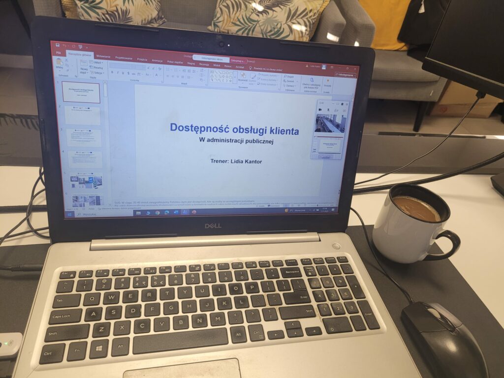 Zdjęcie laptopa z otwarta prezentacją szkolenia oraz kubek kawy obok