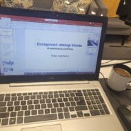 Zdjęcie laptopa z otwarta prezentacją szkolenia oraz kubek kawy obok